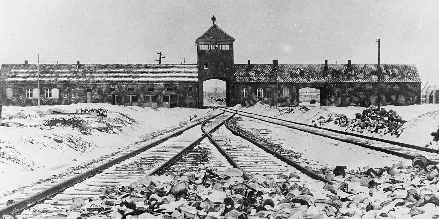 Vernichtungslager Auschwitz-Birkenau: Eingang nach der Befreiung, 1945 Blick auf das Eingangstor von Auschwitz. Im Vordergrund sind Schienen zu sehen., Quelle:
BArch, B 285 Bild-04413 / Mucha, Stanislaw