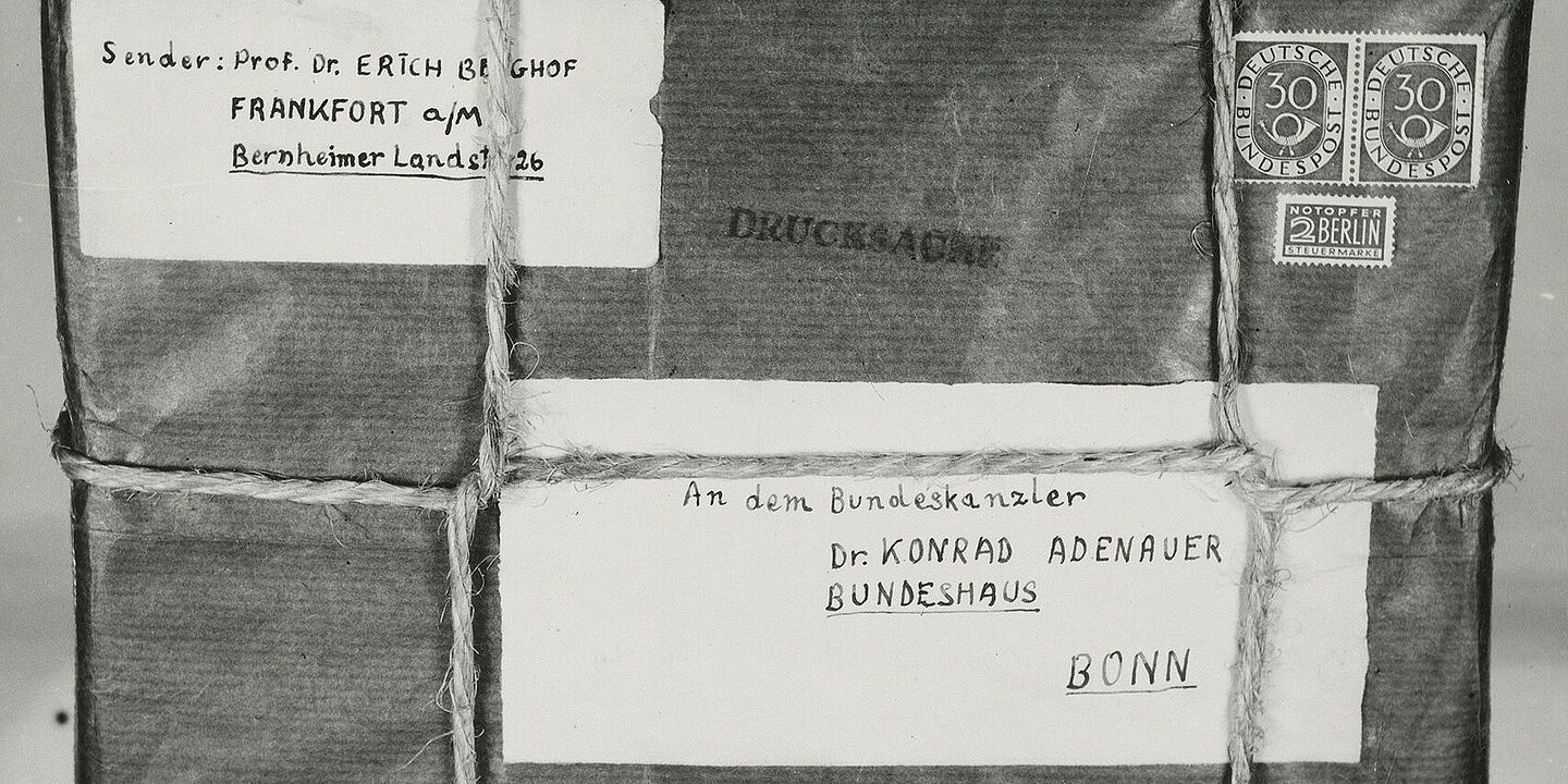 Paketbombe für Konrad Adenauer Aufgeklebtes Schwarz-Weiß-Foto eines mit Band verschnürten Pakets mit handgeschriebener Absender- und Empfängeradresse auf Etiketten, Briefmarken und „Drucksache“-Stempel; an einem darunter angelegten Zollstock ist das Maß ablesbar., Quelle:
BArch, B 106/15789, Image 1133 (Ausschnitt)