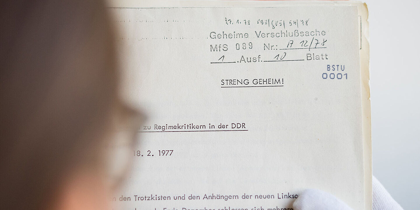 Dreiklang: Geheime Akten öffnen Das Bild zeigt eine Person, die eine geöffnete Akte in den Händen hält und darin liest., Quelle:
BStU / Mulders