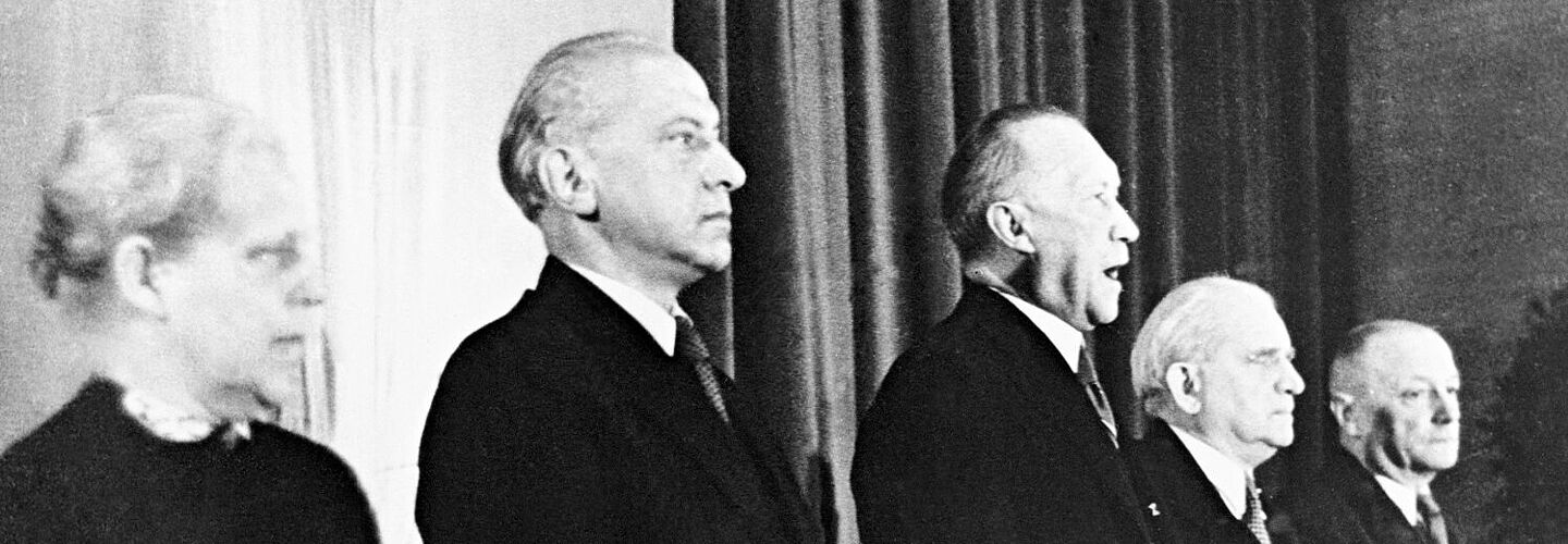 Verkündung des Grundgesetzes Konrad Adenauer, Präsident des Parlamentarischen Rates (M.), verkündet das Grundgesetz (GG) für die Bundesrepublik Deutschland in der Pädagogischen Akademie Bonn (v.l. Helene Weber; Hermann Schäfer; Adolf Schönfelder; Jean Stock).