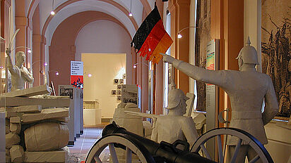 Dauerausstellung in Rastatt Blick in die Dauerausstellung in Rastatt. Zu sehen sind nachgestellte Barrikadenkämpfe: Ein Revolutionär hält ein Schwert hoch, davor stehen zwei preußische Soldaten neben einer Kanone., Quelle:
Hansen