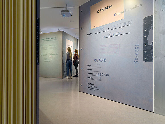 Begehbare Akte Das Bild zeigt Besucherinnen der Ausstellung „Einblick ins Geheime“, die sich die begehbare Akte anschauen