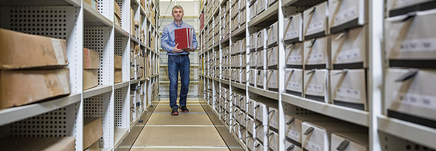 Mitarbeiter des Bundesarchivs zwischen Aktenregalen Mitarbeiter des Bundesarchivs zwischen Aktenregalen