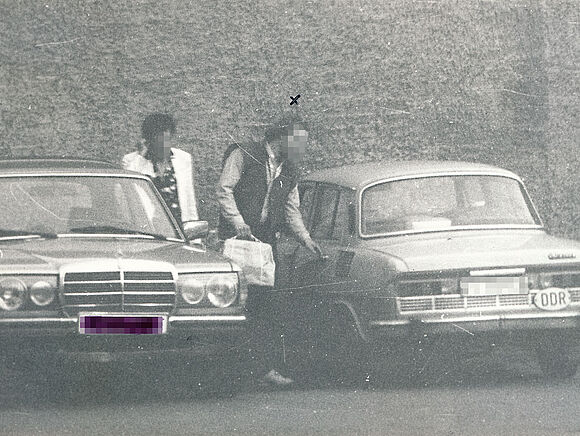 MfS-Beobachtungsfoto im Rahmen des OV "Kassette": Übergabe geschmuggelter Waren auf einem Parkplatz, 1987 Zwei Männer zwischen zwei Autos stehend