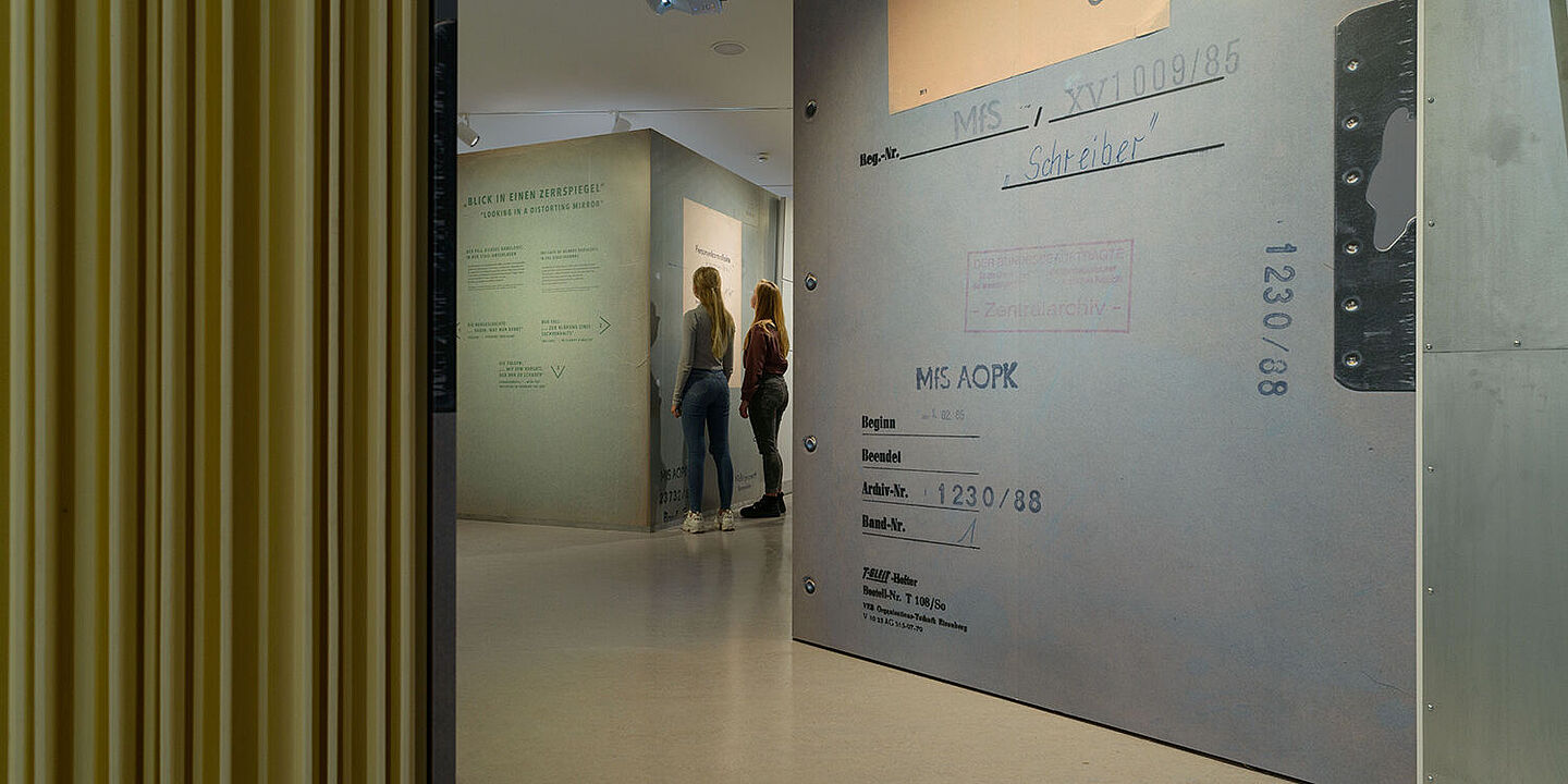 Dreiklang: Über Stasi aufklären Das Bild zeigt zwei Personen in der Ausstellung Einblick ins Geheime. Sie stehen vor einem großen Aktenblatt, Quelle:
BStU/Dresen